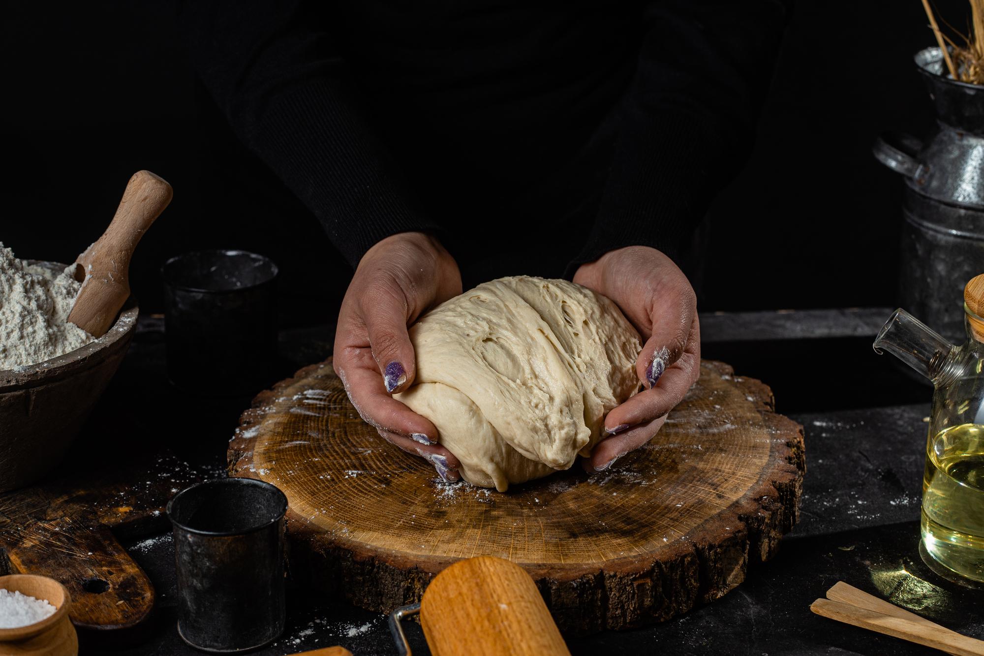 Hands kneading bread on wooden table