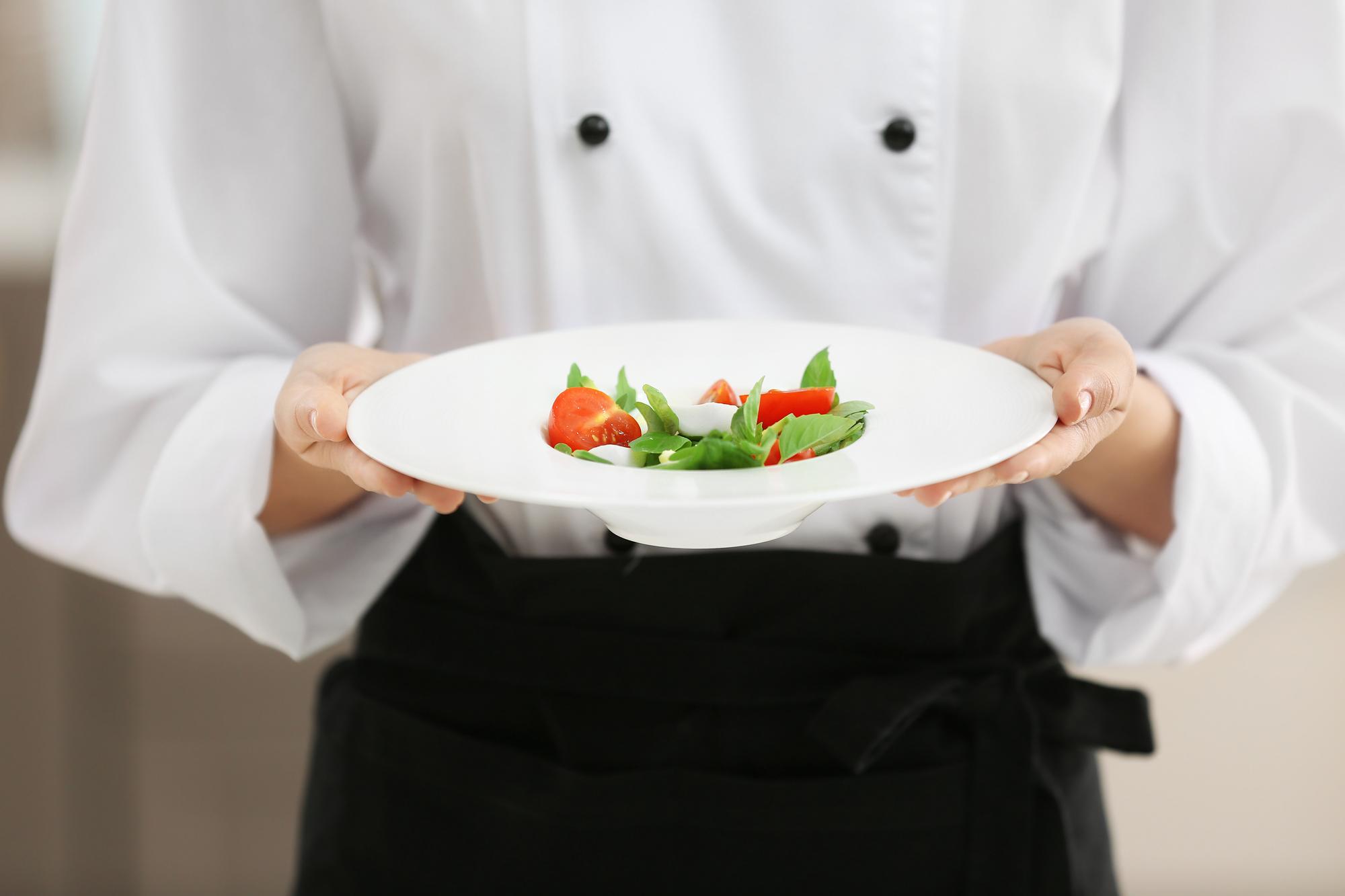 Chef presenting plated dish in modern kitchen